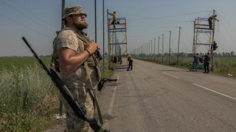 A Ukrainian serviceman stands guard with a shotgun as his fellow soldiers install anti-drone nets over a road at an undisclosed location in the eastern Donetsk region on July 8, 2025, amid the Russian invasion of Ukraine. (Roman Pilipey via Getty Images)