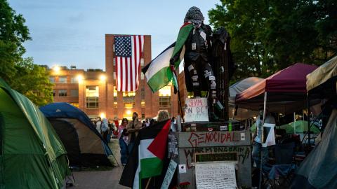 An American flag hangs from the roof of Lisner Hall of the George Washington University Law School as people walk around an encampment at University Yard on May 3, 2024 in Washington, DC. Pro-Palestinian encampments have sprung up at college campuses around the country with some demonstrators calling for schools to divest from Israeli interests amid the ongoing war in Gaza. (Photo by Kent Nishimura/Getty Images)