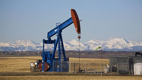 Pumpjack in a field with snow covered mountains in Alberta, Canada. (Michael Interisano/Universal Images Group via Getty Images)