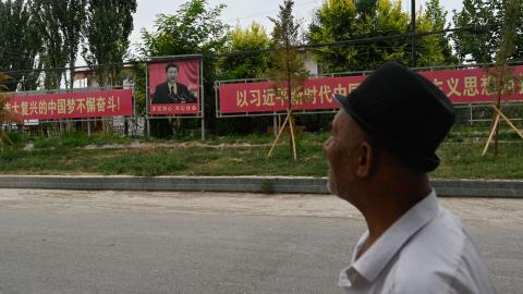 A man passes a portrait of Chinese President Xi Jinping accompanied by a propaganda slogan in Xinjiang, China, on July 16, 2023. (Photo by Pedro Pardo/AFP via Getty Images)