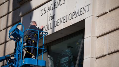 A worker removes the United States Agency for International Development sign on their headquarters on February 7, 2025, in Washington, DC. (Kayla Bartkowski via Getty Images)