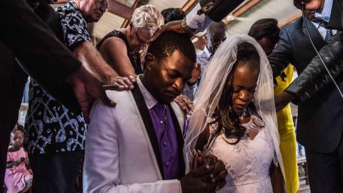 Bride and groom Sharon and McVivien kneel as elders pray over them following their nuptials mass during their wedding ceremony in Nairobi, Kenya, on February 13, 2016. (Fredrik Lerneryd/AFP via Getty Images)