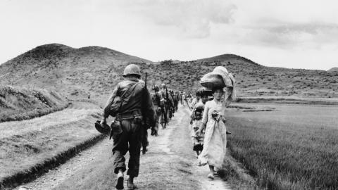 As US infantrymen march into the Naktong River region, they pass a line of refugees on August 11, 1950. (Getty Images)