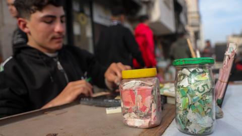 A Palestinian teenager repairs worn and damaged banknotes due to the prolonged shortage of new currency entering the Gaza Strip on February 12, 2026. (Getty Images)