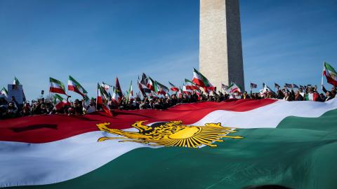 Caption Demonstrators hold a large Iranian flag dating from before the 1979 Islamic revolution during a march in support of the people of Iran in Washington, DC, on February 14, 2026. (Getty Images) 