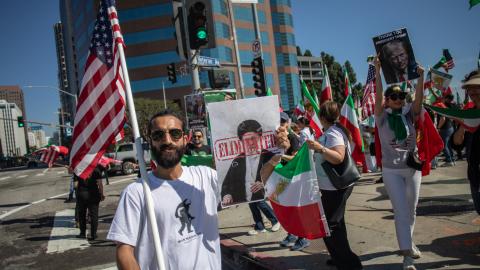 A man holds a US flag and a sign with a portrait of the late Supreme Leader Ayatollah Ali Khamenei as members of the Iranian community celebrate in Los Angeles on February 28, 2026. (Getty Images)