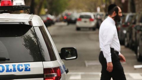 A Hasidic man walks by a police car in a Jewish Orthodox neighborhood in Brooklyn on April 24, 2017 in New York City.
