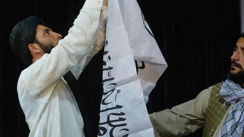Men adjust the Taliban flag before the arrival of Taliban spokesperson Zabihullah Mujahid (unseen) to address the first press conference in Kabul on August 17, 2021 following the Taliban stunning takeover of Afghanistan. (Photo by Hoshang Hashimi / AFP)