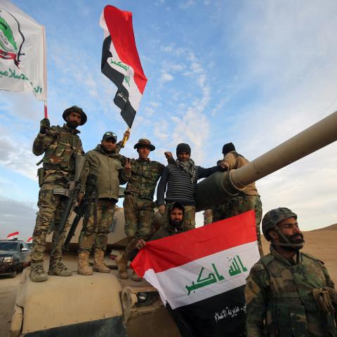 Iraqi paramilitaries of Asa'ib Ahl al-Haq wave their flag and the national flag on November 25, 2017. (Ahamad al-Rubaye/AFP via Getty Images)