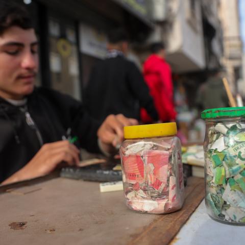 A Palestinian teenager repairs worn and damaged banknotes due to the prolonged shortage of new currency entering the Gaza Strip on February 12, 2026. (Getty Images)